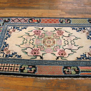 Floral and geometric pattern rug featuring cream, pink, blue, black, and coral colors on wood flooring.