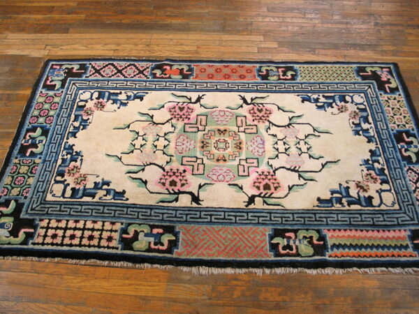 Floral and geometric pattern rug featuring cream, pink, blue, black, and coral colors on wood flooring.