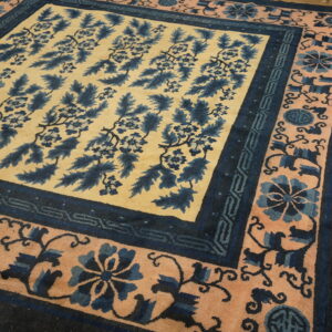 Navy blue and cream rug with foliage motif and blush borders displayed on light wood planks.