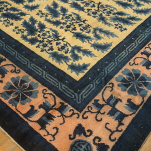 Yellow, dark blue, and peach patterned rug corner rests on light brown wooden floorboards.