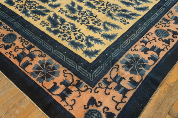 Yellow, dark blue, and peach patterned rug corner rests on light brown wooden floorboards.