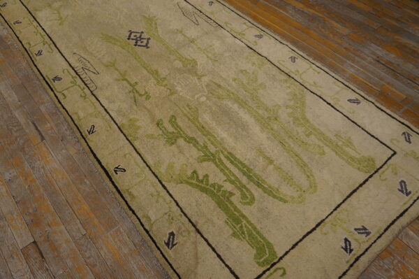 Low-pile runner in light tan and vivid green abstract patterns on distressed, rustic hardwood floors.