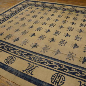 Low pile beige and indigo rug featuring stylized motifs, displayed on distressed wood planks.