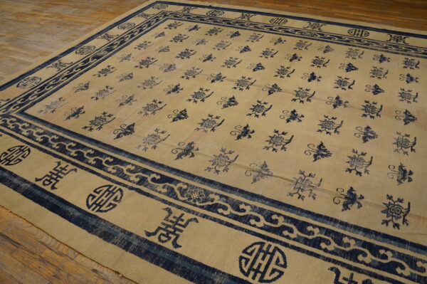 Low pile beige and indigo rug featuring stylized motifs, displayed on distressed wood planks.