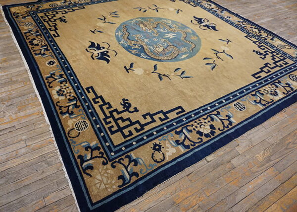 Low-pile beige rug with complex blue geometric and dragon patterns rests on distressed wooden floors.