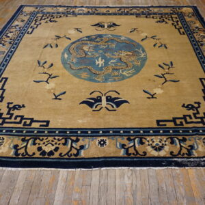Tan and blue rug featuring two dragons in a central medallion, displayed on distressed wooden floorboards.