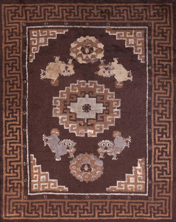Dark brown rug featuring a geometric key pattern border, central medallion, and stylized animal figures in tan and gray.