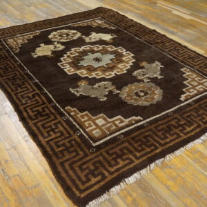 Dark brown rug featuring geometric and central medallion patterns in tan and light gray on rustic wood floors.