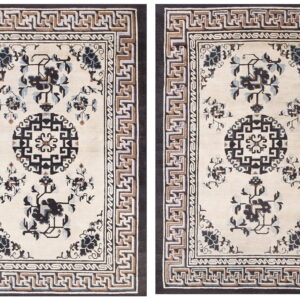 Beige rug with dark botanical motifs, a black central medallion, and layered geometric key pattern borders.