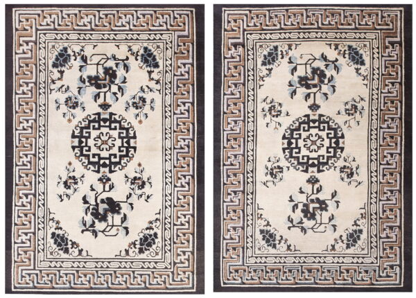 Beige rug with dark botanical motifs, a black central medallion, and layered geometric key pattern borders.