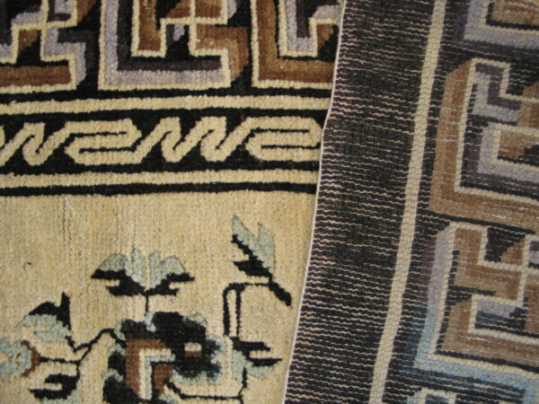 Beige pile rug with black, brown, and blue floral and key patterns beside a tightly woven dark geometric texture.