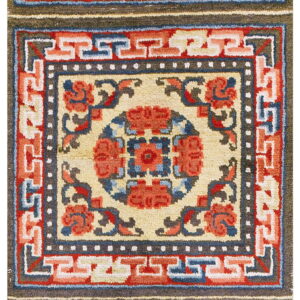 Geometric runner rug with repeated medallions and Greek key borders in cream, red, blue, and olive.