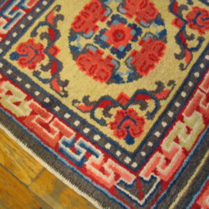 Multicolor geometric and floral rug featuring bright red, yellow, and blue patterns rests on wood plank flooring.