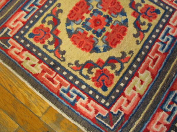 Multicolor geometric and floral rug featuring bright red, yellow, and blue patterns rests on wood plank flooring.