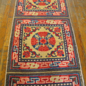Low-pile runner with bold red, blue, and yellow squares and key fret borders on wood planks.