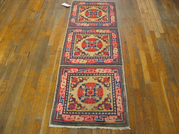 Colorful runner rug displaying repeated red, blue, and yellow medallions with geometric borders on wood flooring.
