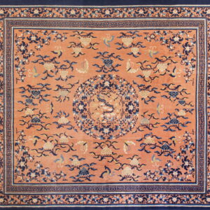Low-pile rug with a coral field, detailed navy and cream floral patterns, and a complex dark blue border.