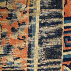 Close-up showing contrasting flatweave and high pile rug textures in coral, navy, light blue, and cream.