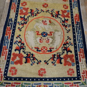 Medium pile rug with a tan field, featuring a central bird design and elaborate red and blue geometric borders.
