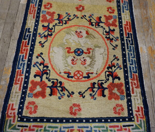 Medium pile rug with a tan field, featuring a central bird design and elaborate red and blue geometric borders.