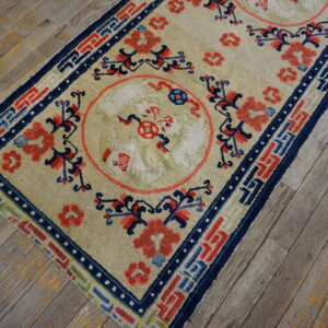 Beige rug runner with coral and navy blue medallions rests diagonally on weathered wood flooring.