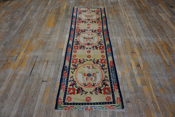Light yellow runner rug featuring red and blue medallions sits centered on distressed gray wood planks.