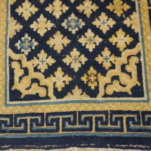 Navy and mustard yellow rug featuring quatrefoil medallions and a complex Greek key border.