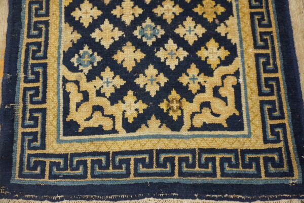 Navy and mustard yellow rug featuring quatrefoil medallions and a complex greek key border.