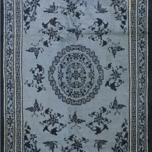 Slate blue rug with high-contrast dark indigo floral and butterfly designs and complex geometric borders.