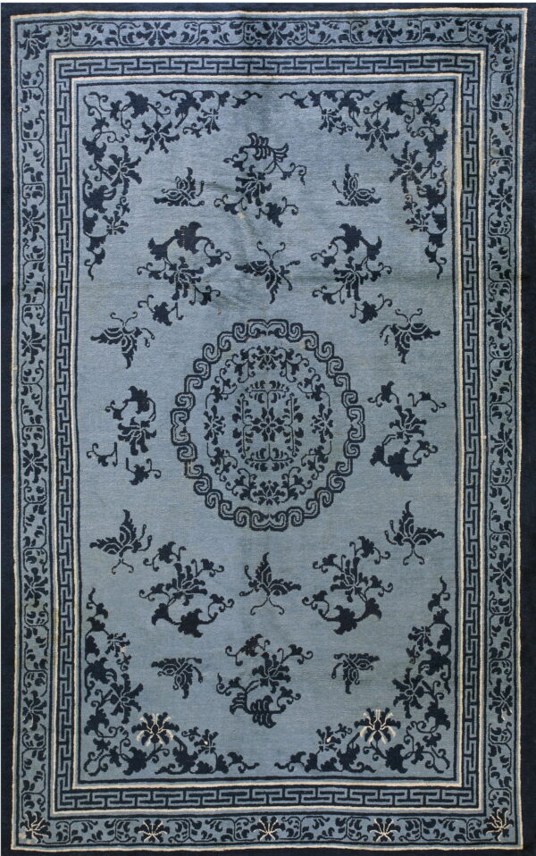 Slate blue rug with high-contrast dark indigo floral and butterfly designs and complex geometric borders.