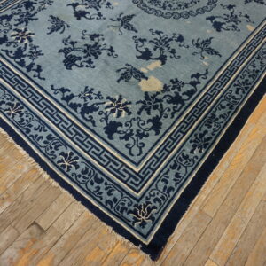 Navy blue and light blue floral rug featuring a geometric border on distressed wood plank flooring.