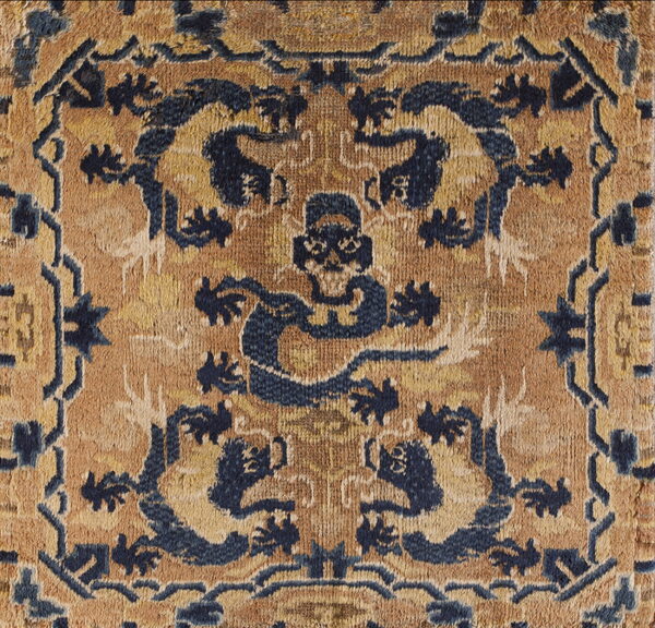 Intricate blue and tan high-pile rug detail showing stylized animal figures and a geometric border design.