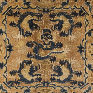 Distressed rug detail featuring symmetrical dark blue designs against a mottled golden-yellow field.