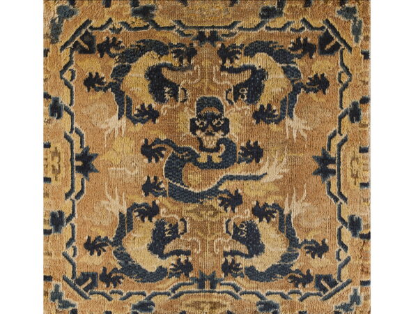 Distressed rug detail featuring symmetrical dark blue designs against a mottled golden-yellow field.