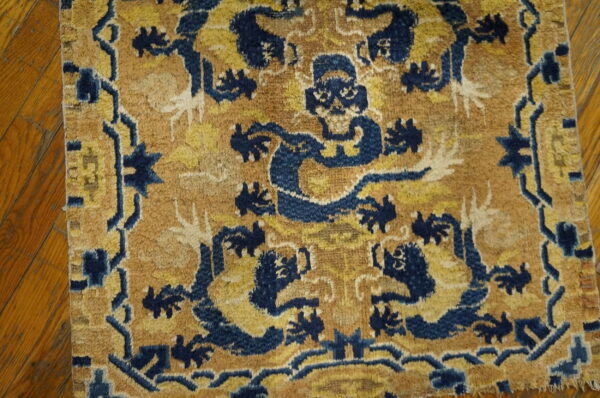 A high-pile rug with stylized blue dragon motifs and gold-tan colors rests on wood flooring.