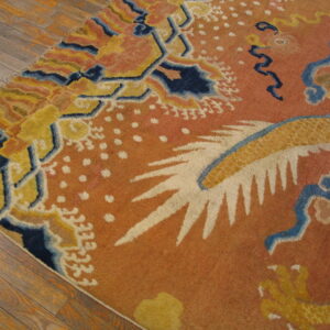 A colorful area rug with bold orange, yellow, and navy blue patterns sits on rustic wood flooring.