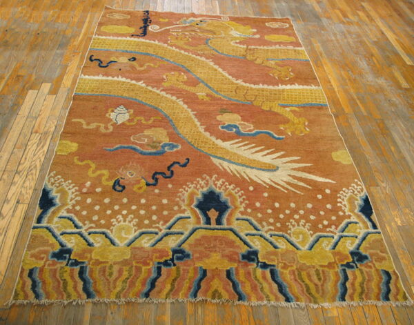 Yellow dragon and blue cloud motifs dominate this rust-colored rug resting on wooden floorboards.