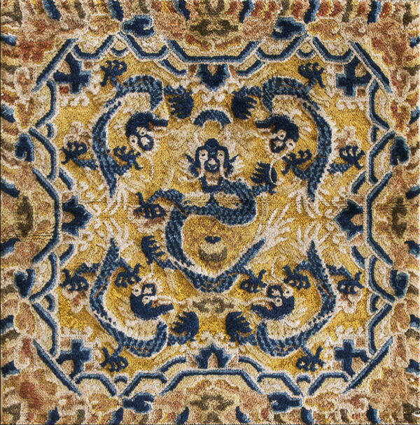 Detailed, high-pile rug section featuring stylized dragons and mythical faces in gold and navy blue.