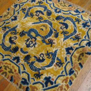 Yellow high-pile rug with a dark blue dragon pattern rests on rustic wooden floorboards.