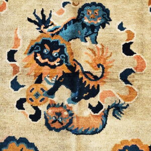 Beige rug featuring a detailed pattern of blue and orange stylized animals and swirling abstract shapes.