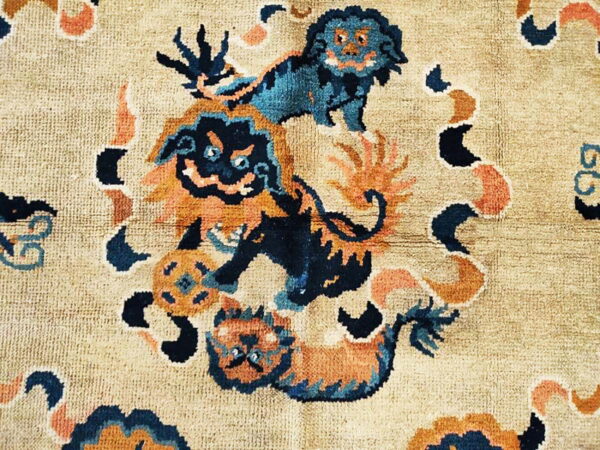 Beige rug featuring a detailed pattern of blue and orange stylized animals and swirling abstract shapes.