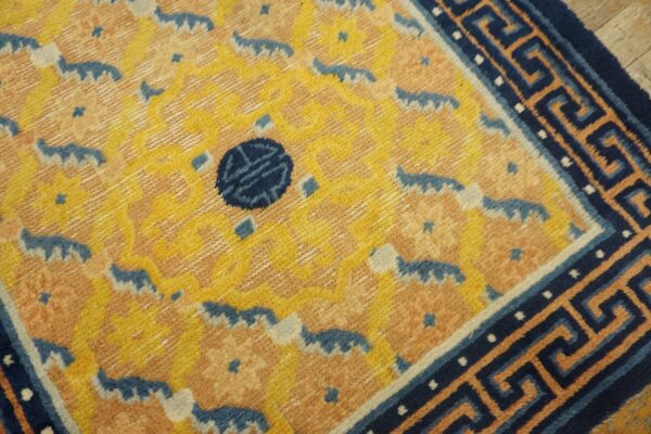 High-pile rug featuring a yellow and salmon pattern, a dark blue medallion, and a striking greek key border.