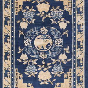Dense blue rug with beige borders, traditional floral pattern, geometric motifs, and a central medallion design.