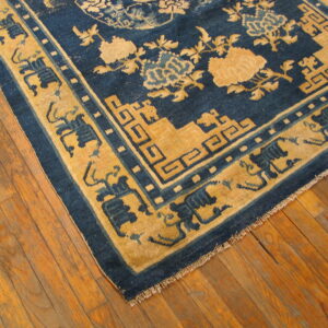 Blue and gold patterned rug with floral and geometric motifs rests on rustic hardwood flooring.