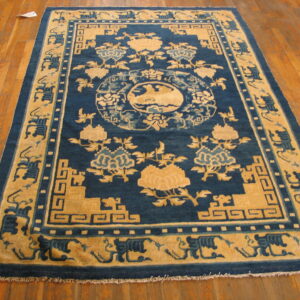 Rectangular blue and tan patterned rug with thick borders displayed on polished hardwood flooring.