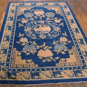 Deep blue and tan rug with an ornate floral and geometric pattern on a polished wood floor.