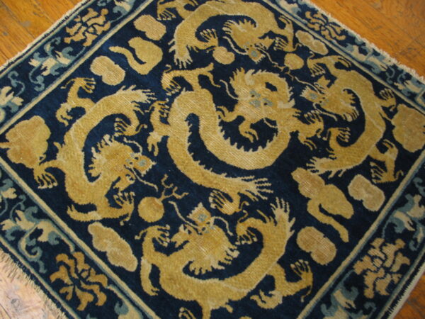 A dark blue rug featuring a large gold and teal mythical dragon pattern rests on a hardwood floor.