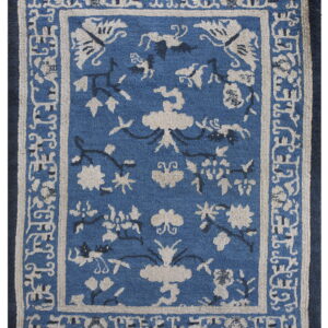 Medium-pile blue rug featuring beige and dark blue stylized floral and vine patterns within intricate borders.