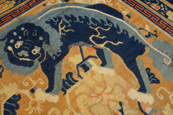 Close-up of a medium-pile rug in indigo, light blue, and tan featuring a stylized mythical creature design.