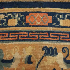Detailed view of a rug with navy, rust, and gold border featuring fretwork and floral motifs.
